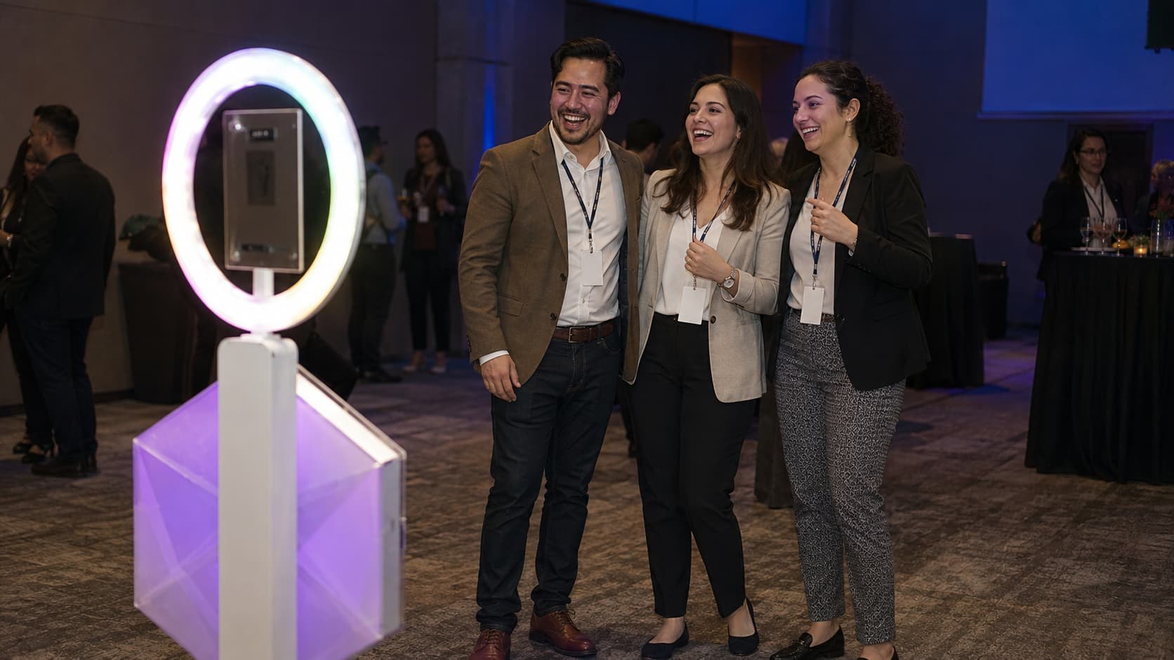 Tres invitados riendo frente al Booth Robot con aro de luz en un evento corporativo